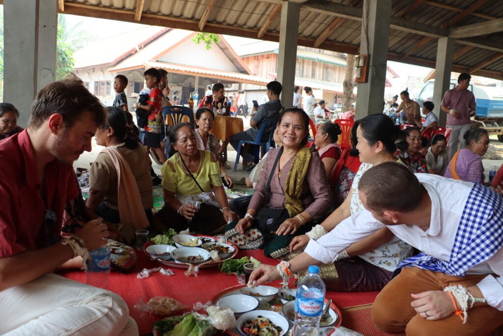 Repas partagé entre des laotiens et touristes dans un village après une cérémonie de Baci.