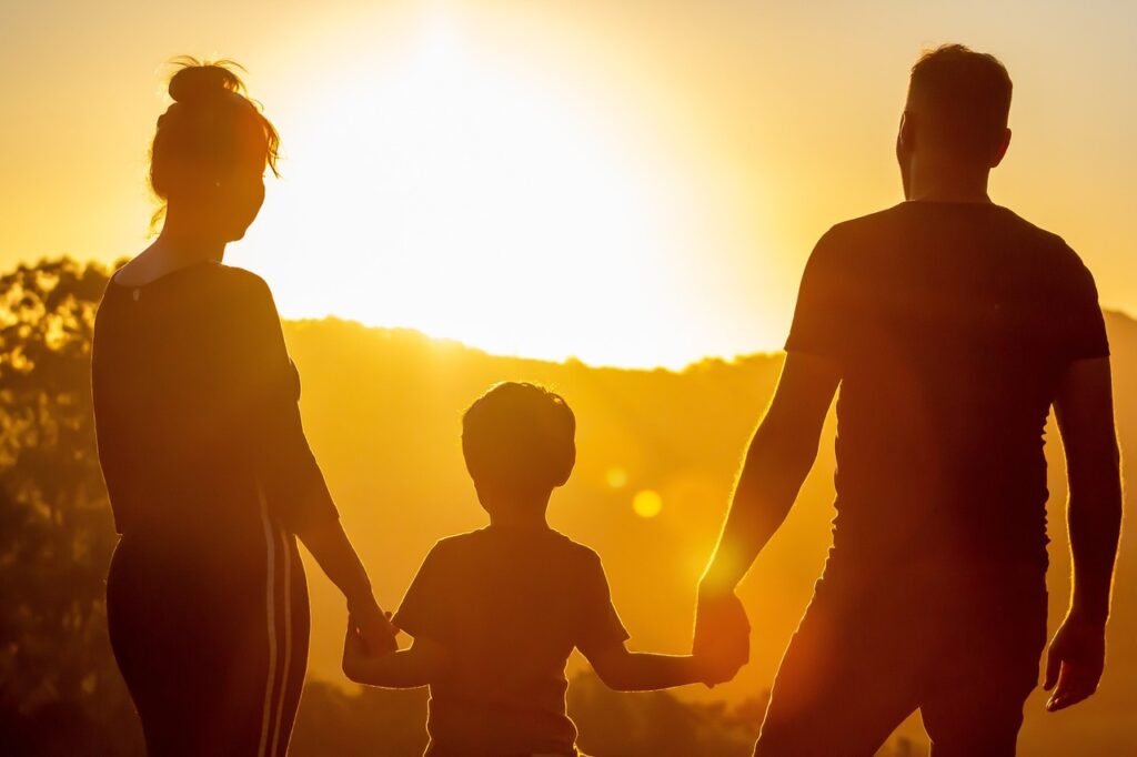 Une famille contemplant un coucher de soleil à l’horizon ensemble.